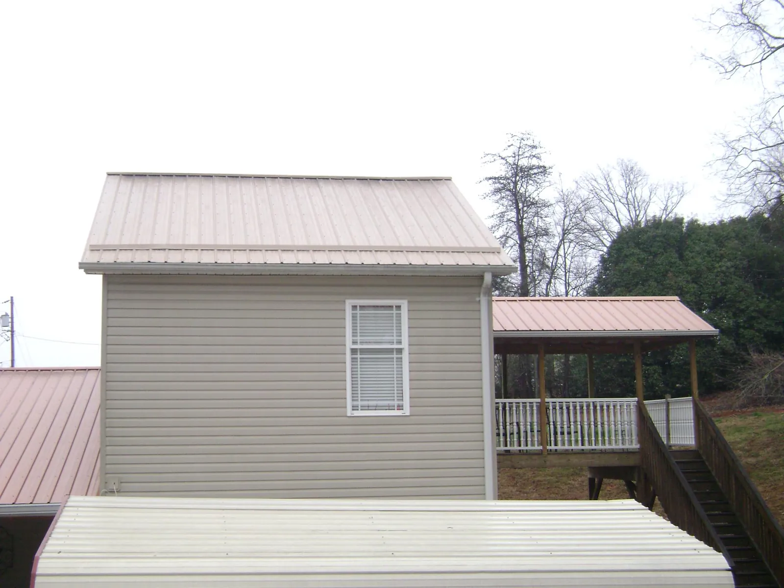 Tan metal roofs on a two story addition and attached porch, from a Roof Replacement job in River Rouge